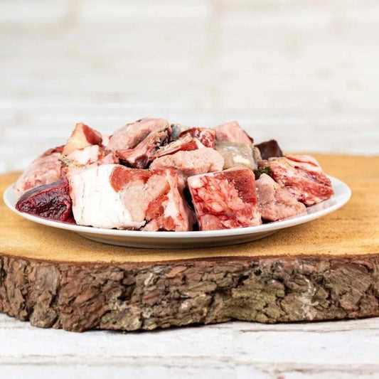Lammfleisch in Stücken auf einem Teller, ideal für BARF-Ernährung von Hunden ab 15 kg.