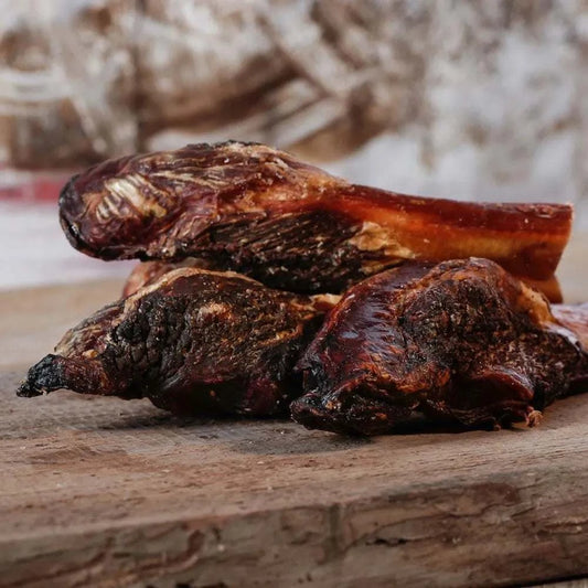 Getrocknete Fleischkeule 10-15 cm als Kaubeschäftigung für Hunde, platziert auf einem Holzbrett.