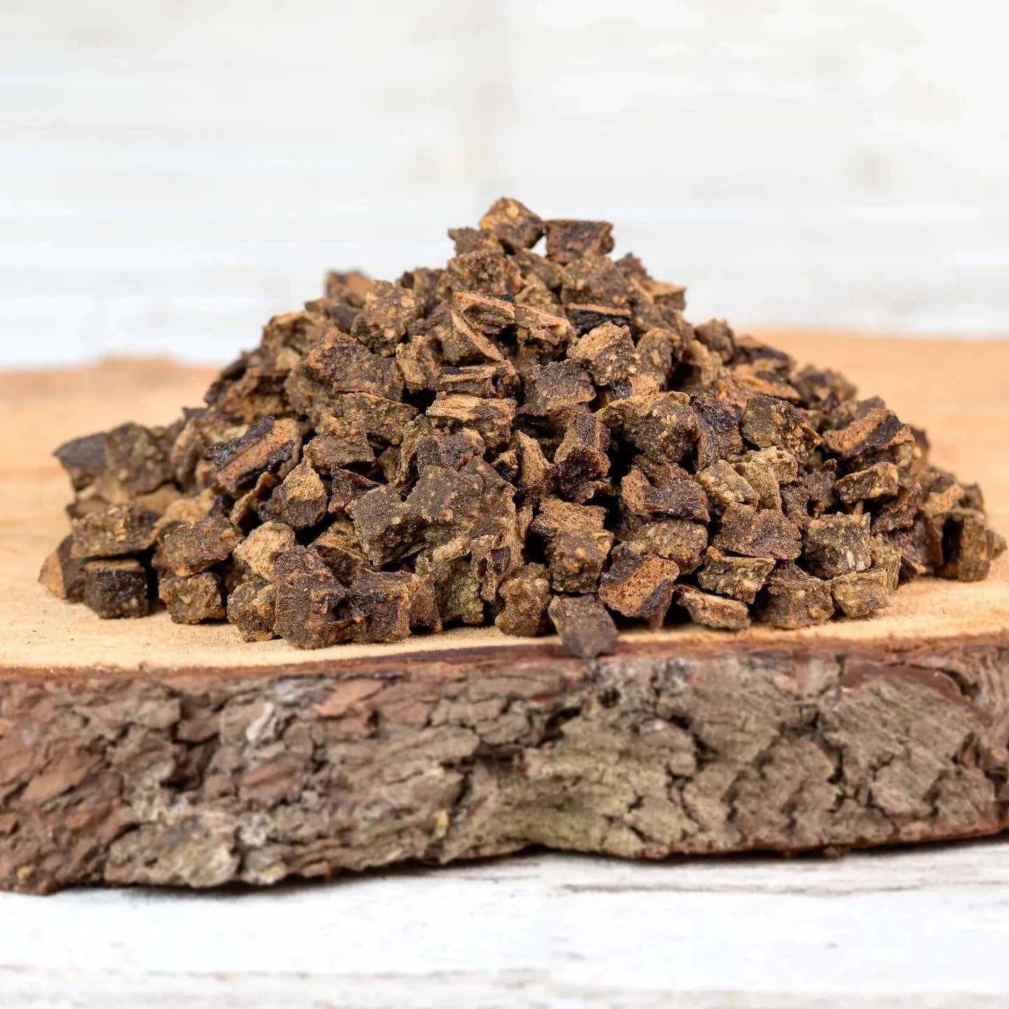 Wildfleischwürfel als Hundesnack, 100 % Wildfleisch, platziert auf einem Holzbrett.