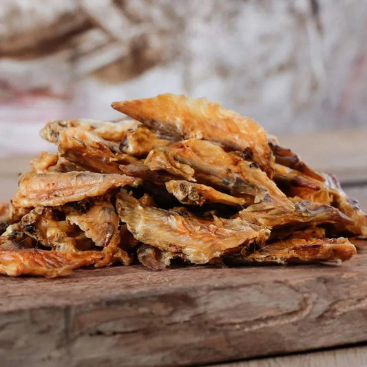 Hühnerflügel für Hunde und Katzen auf Holzbrett, getrocknet, Naturkauartikel.