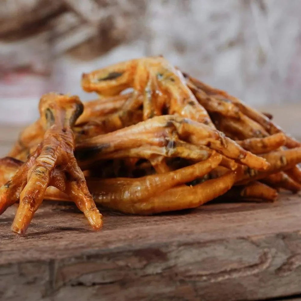 Hühnerfüße auf Holzbrett, leicht verdaulich, reich an Calcium, für Hunde und Katzen geeignet, Naturkauartikel.