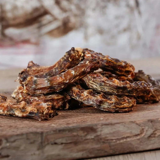 Hühnerhälse auf Holzbrett, reich an Calcium, idealer Snack für kleine Hunde und Katzen.