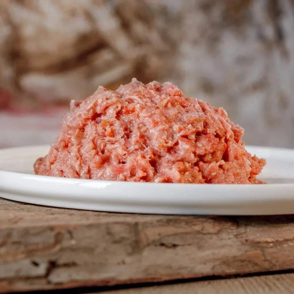 BARF-Komplettmenü Huhn, gewolft, auf weißem Teller, ausgewogenes Verhältnis aus Huhn und Gemüse, ideal für Hunde und Katzen.