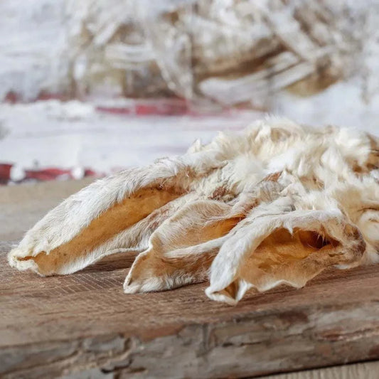 Kaninchenohren mit Fell auf Holzbrett, natürlicher Kausnack für Hunde und Katzen.