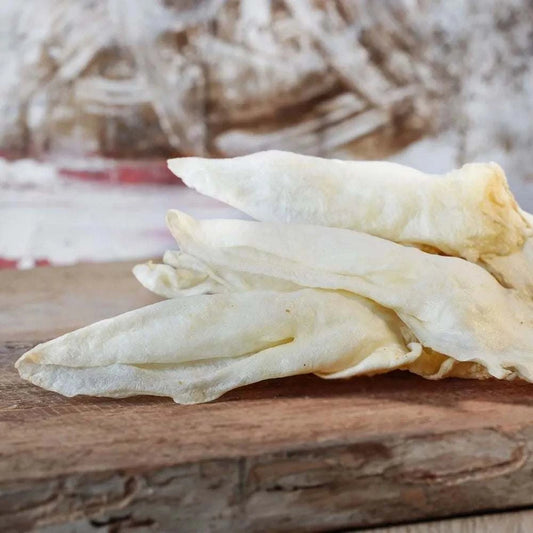 Kaninchenohren ohne Fell auf Holzbrett, natürlicher Kauartikel für Hunde und Katzen.