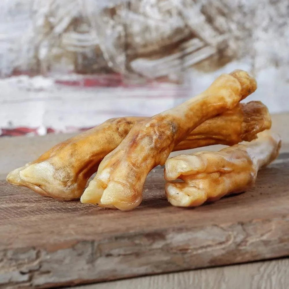 2 getrocknete Lammbeine auf Holzbrett, proteinreicher und calciumhaltiger Kausnack für Hunde.