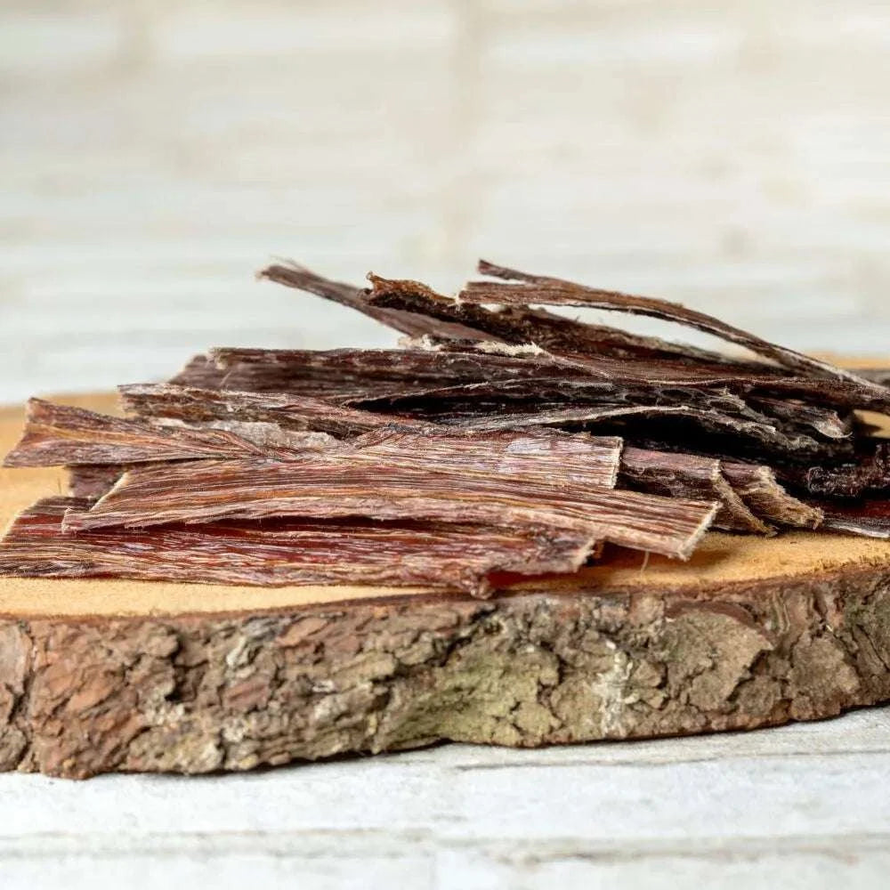 Pferdefleischstreifen auf Holzbrett, Naturkauartikel für Hunde.