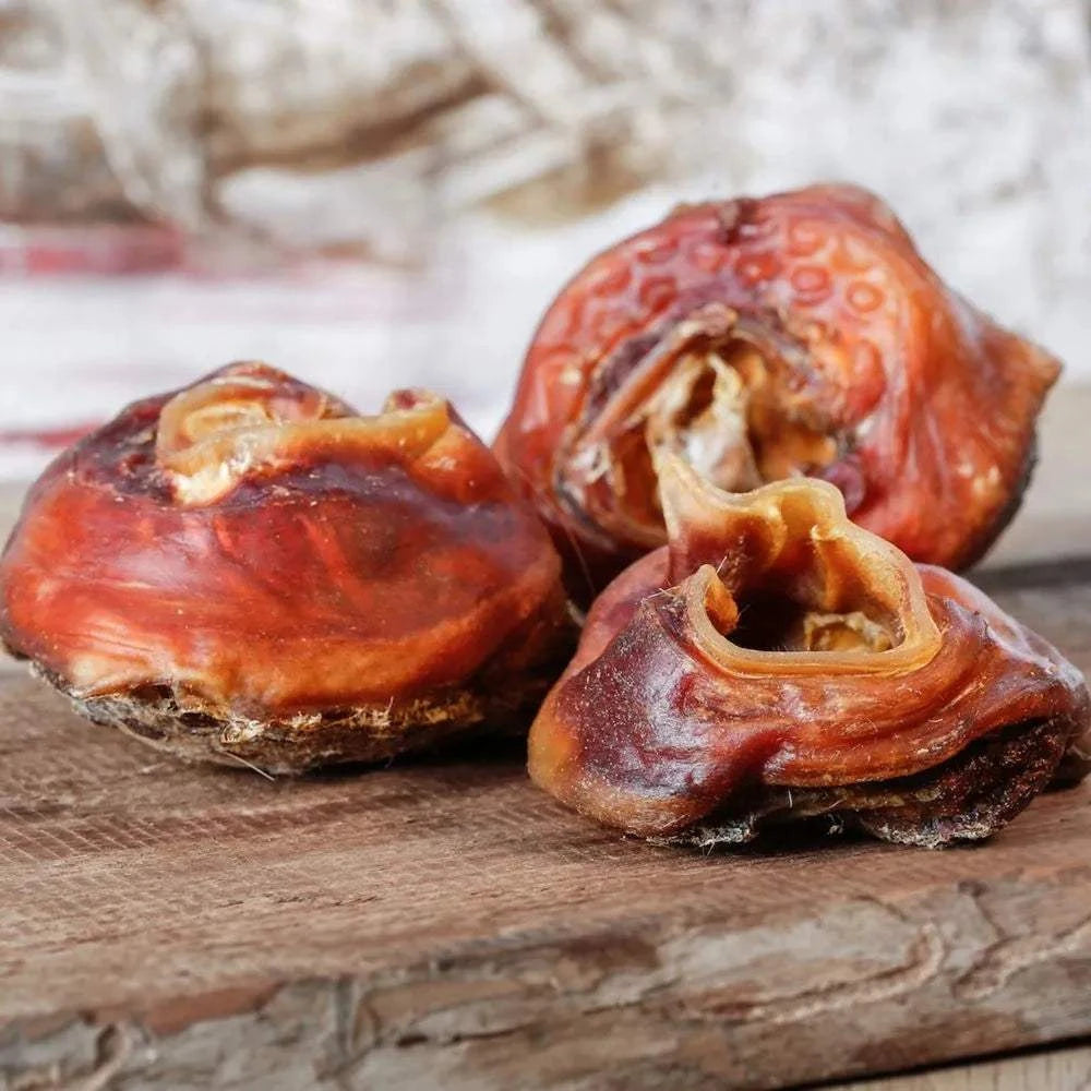 Rinderohrmuscheln ohne Fell, gebrüht, platziert auf Holzbrett, als kalorienarmer Snack für Hunde.