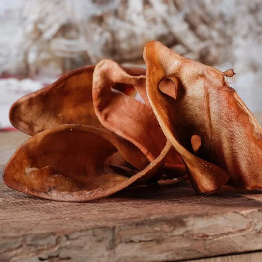 Schweineohren aus getrocknetem Schweinefleisch, platziert auf einem Holzbrett.