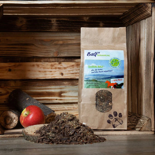 TrockenBARF BALF Pferd 1.000 g Beutel , platziert auf einem Holzbrett und mit einem roten Apfel, ideale Vollnahrung für Hunde unterwegs.