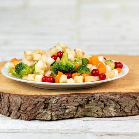 Bunter Gartenmix aus Obst und Gemüse auf Holzbrett, ideal für Hundeernährung.