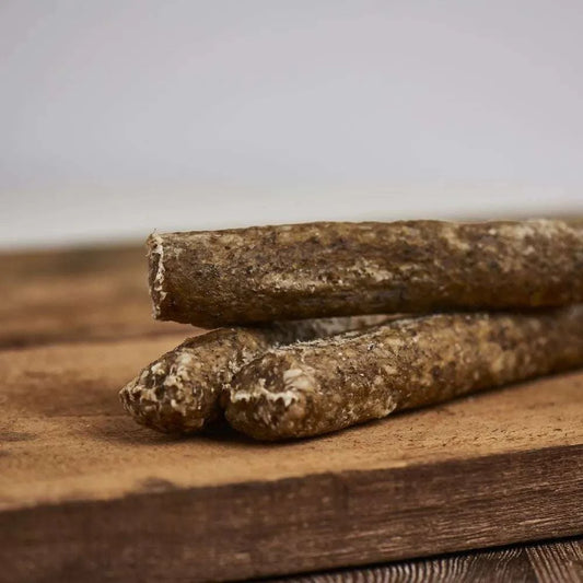 Knusperstange Elch XL, 18 cm, Kausnack für Hunde mit Karotte, Petersilie und Seetang, platziert auf einem Holzbrett.