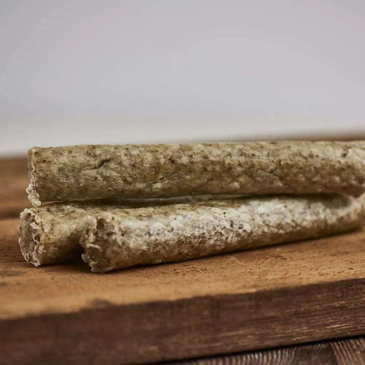 Knusperstange Rind XL im 2er Pack, ca. 18 cm lang, geeignet für Hunde, mit Karotte, Petersilie und Seetang, platziert auf einem Holzbrett.