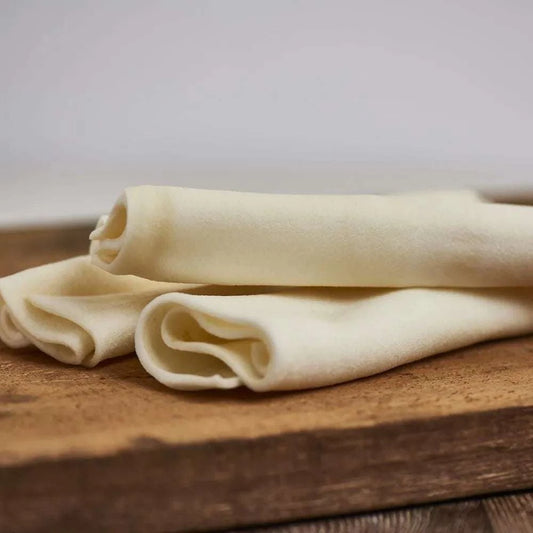 Naturkaurolle Rind XL, 25 cm lang, handgerollt, für große Hunde, geruchsneutral, platziert auf einem Holzbrett.