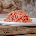 BARF-Komplettmenü Huhn, gewolft, auf weißem Teller, ausgewogenes Verhältnis aus Huhn und Gemüse, ideal für Hunde und Katzen.